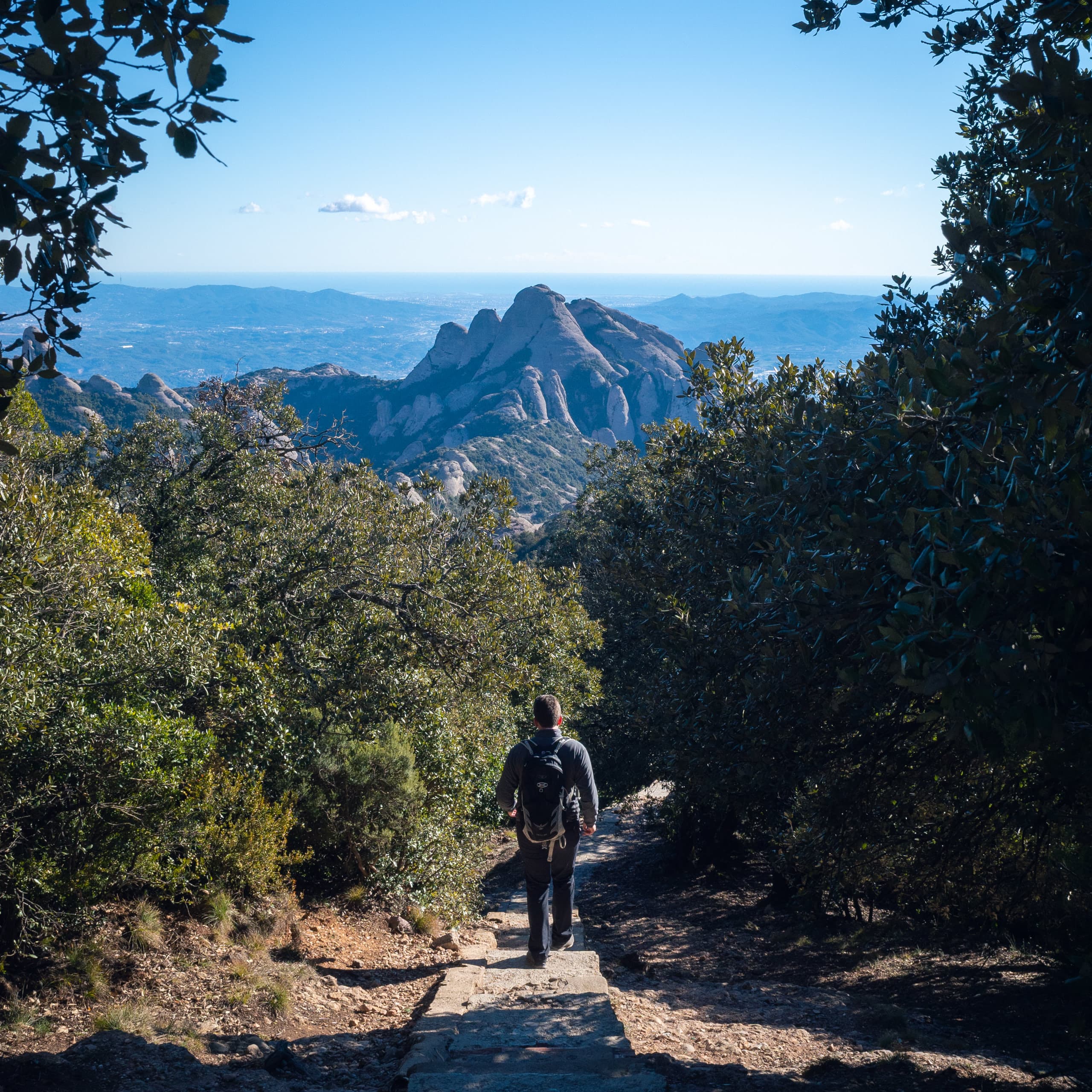 A man walking down the stairs overlooking round-looking mountains in the distant