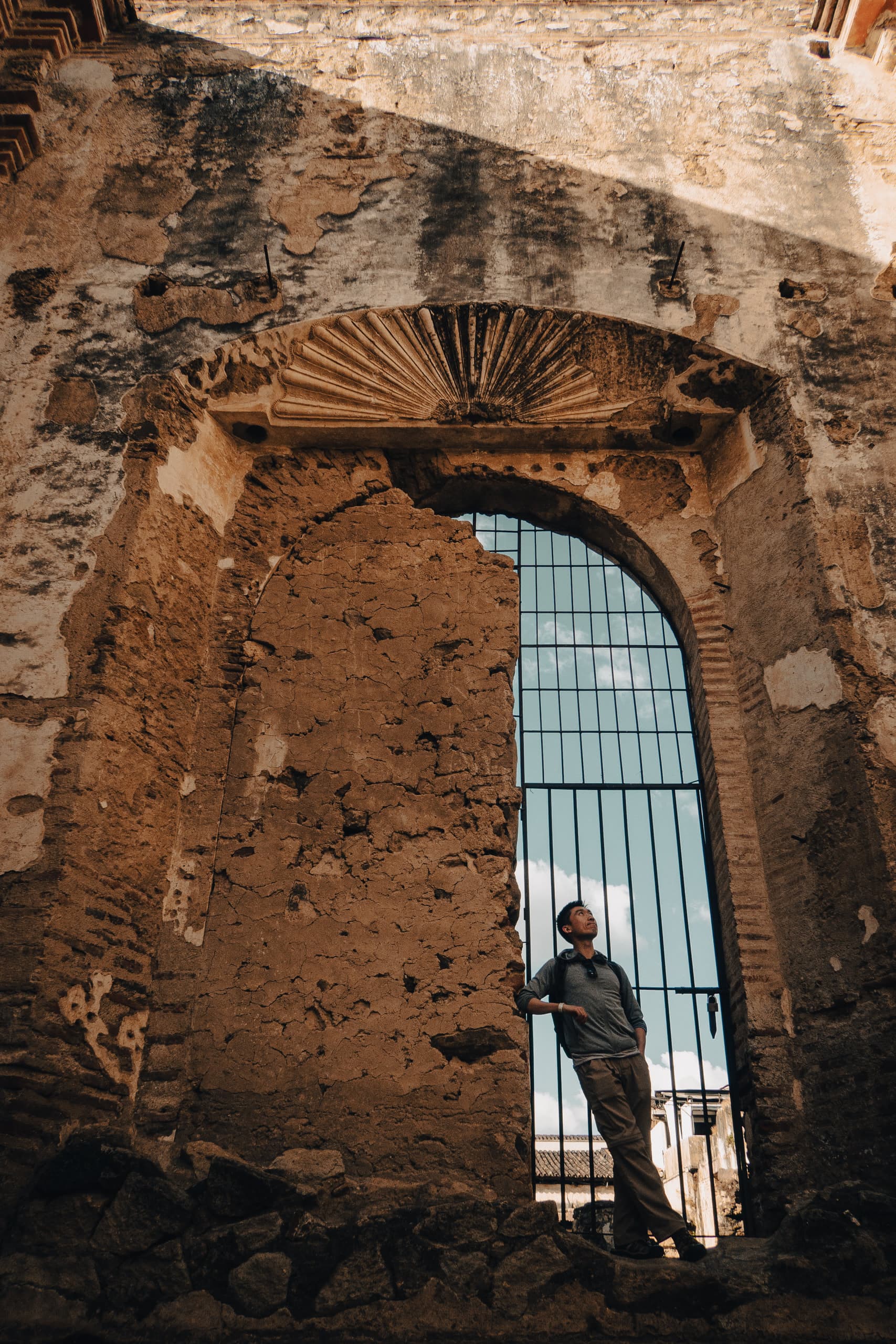 Man standing by a crumbling gate and wall