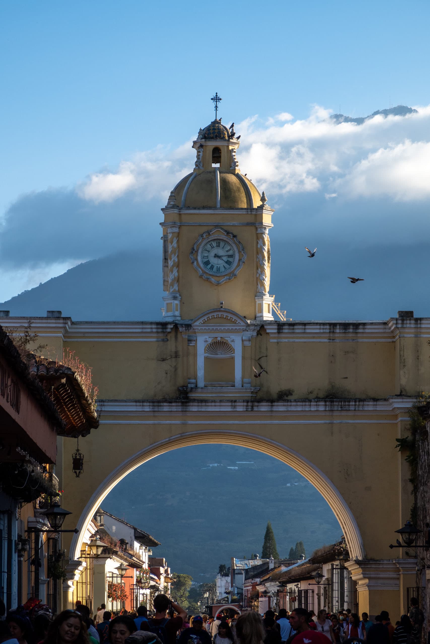 Yellow arch with crowd of people at the bottom and a dormant volcano in the background