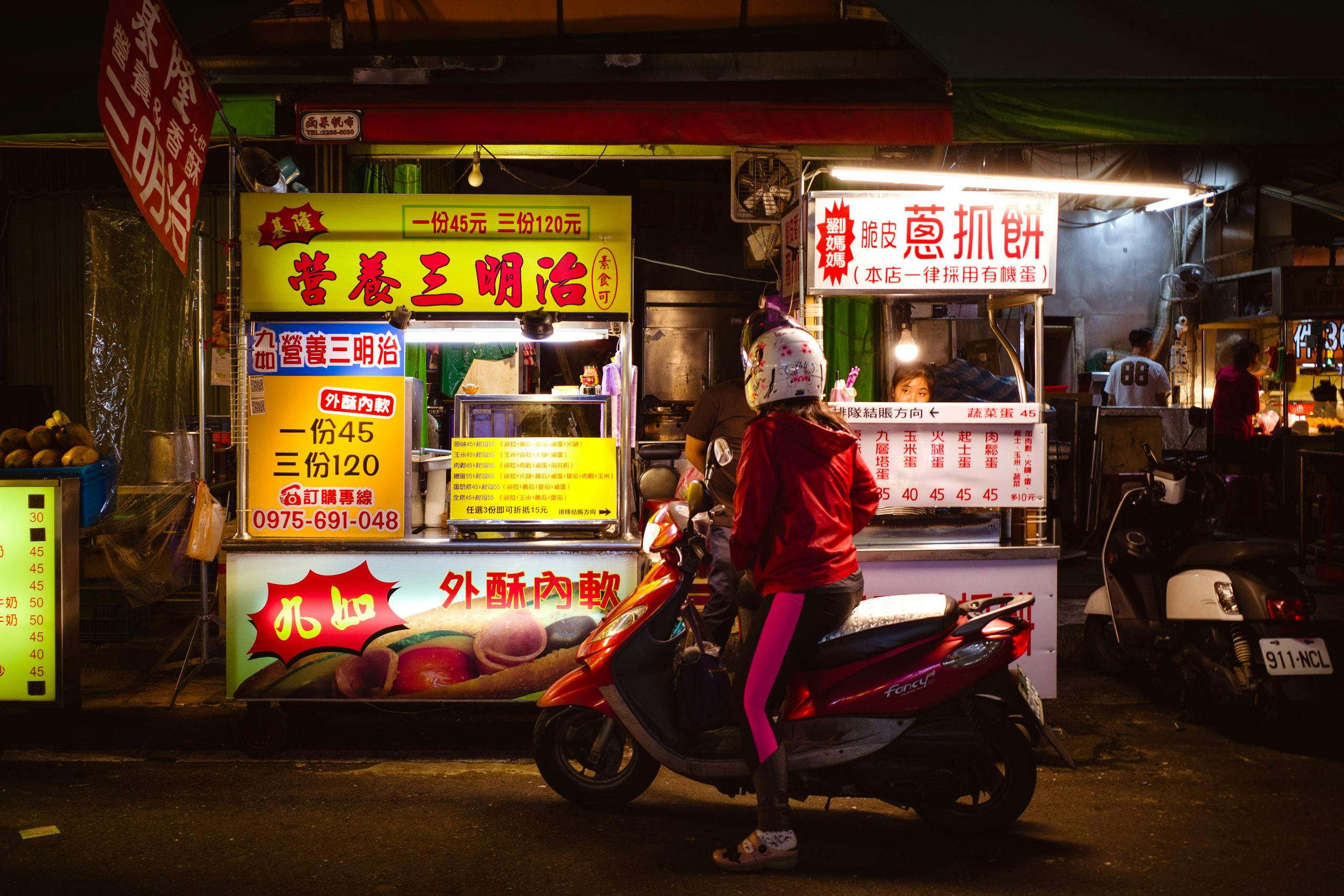 A person on a scooter in front of a food stand
