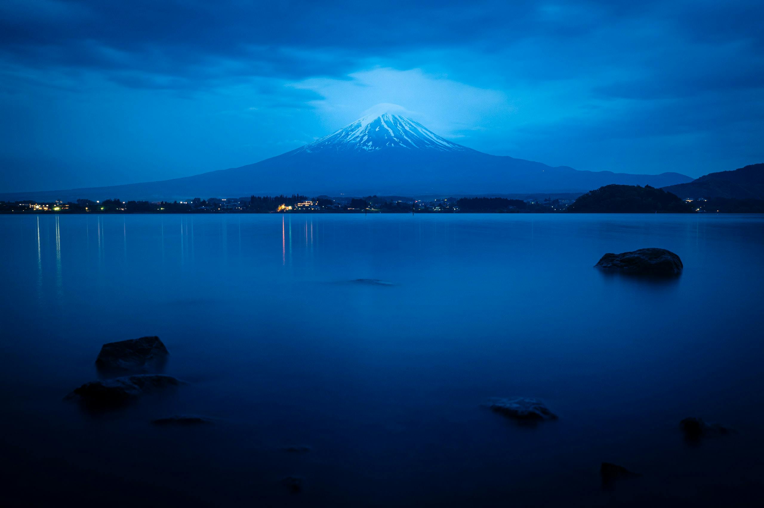 A lake with Mount Fuji at a distance at dusk