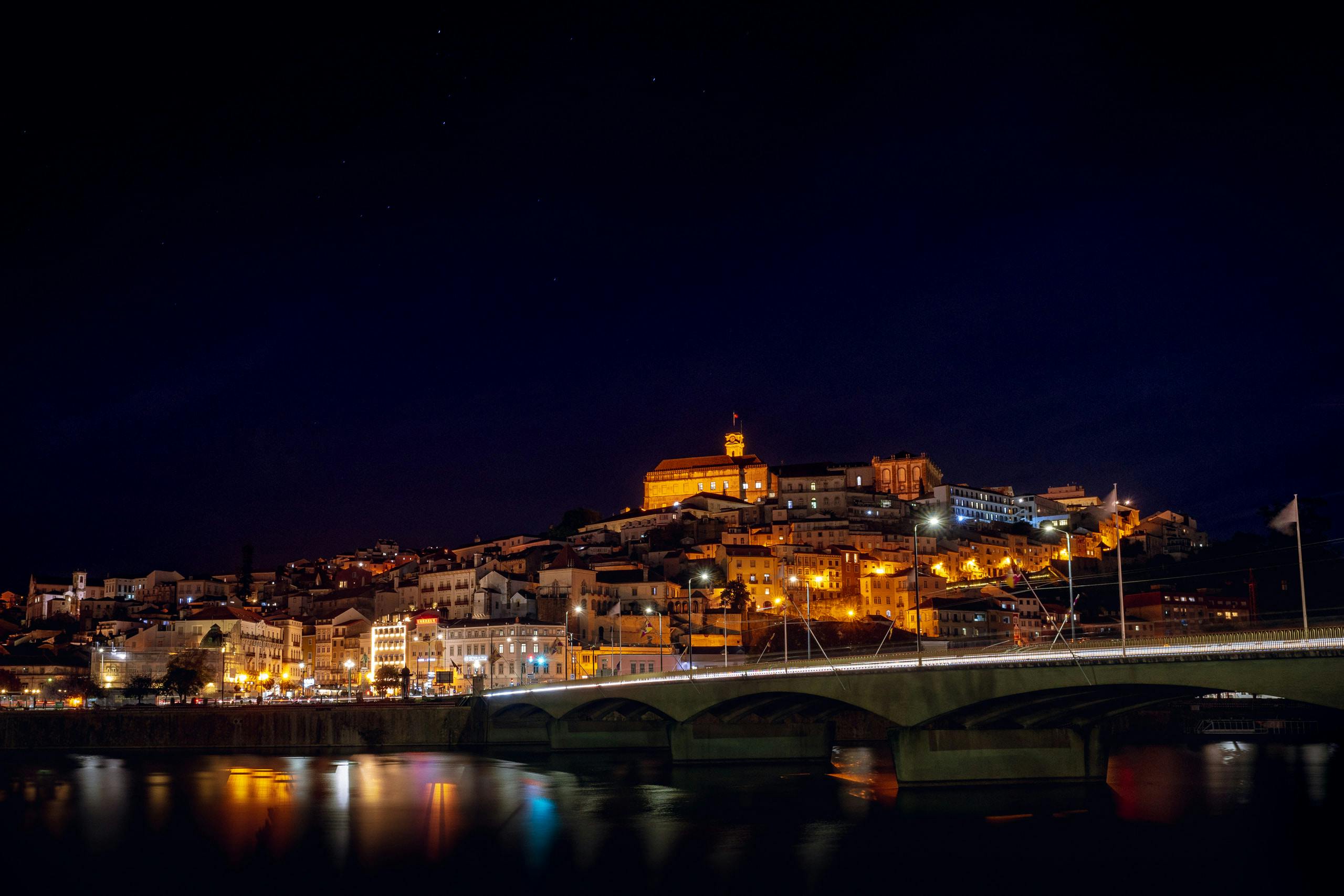 City of Coimbra in the night by the river with a bridge on the right