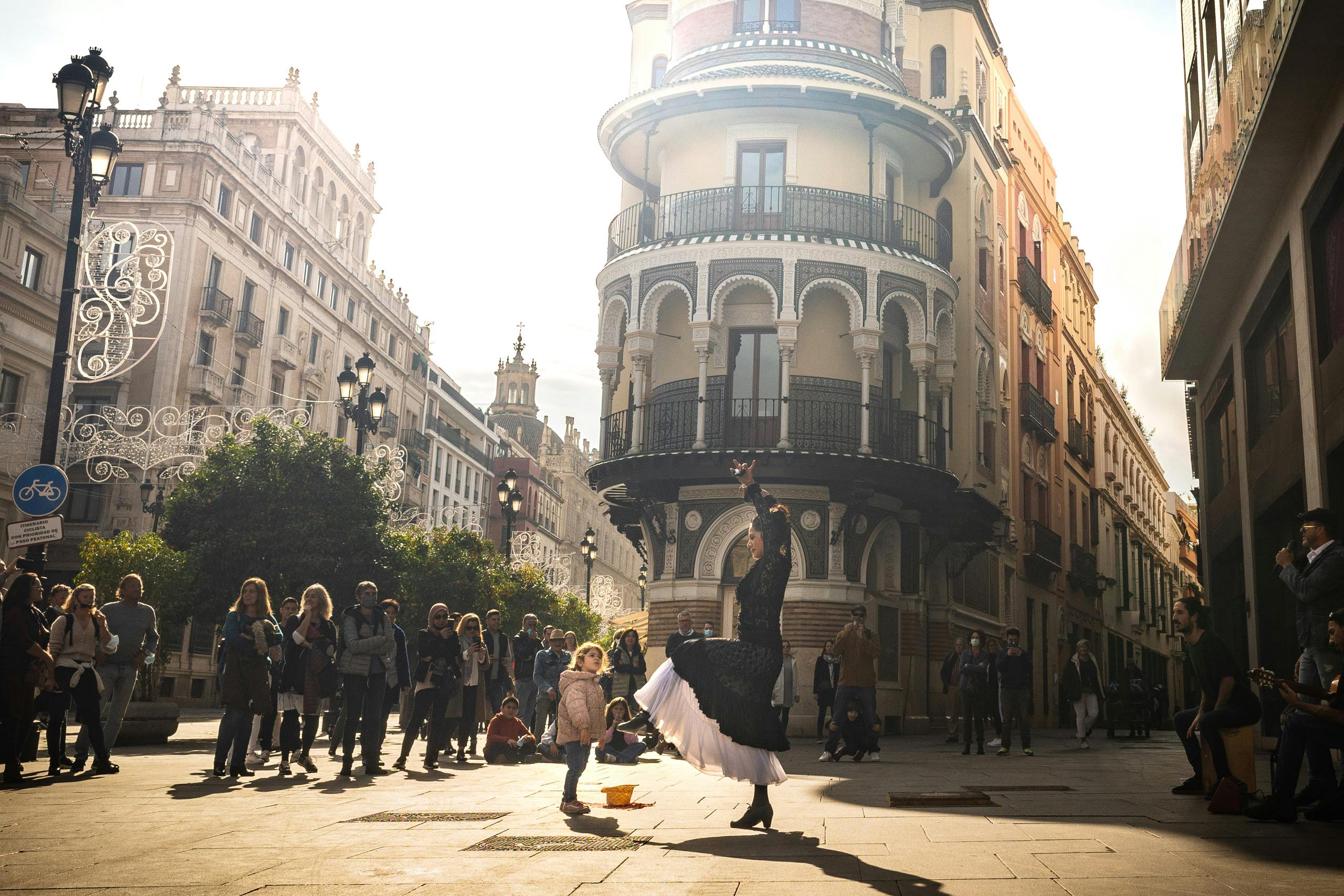 Flamenco dancer flourishes in front of young girl in the middle of the street